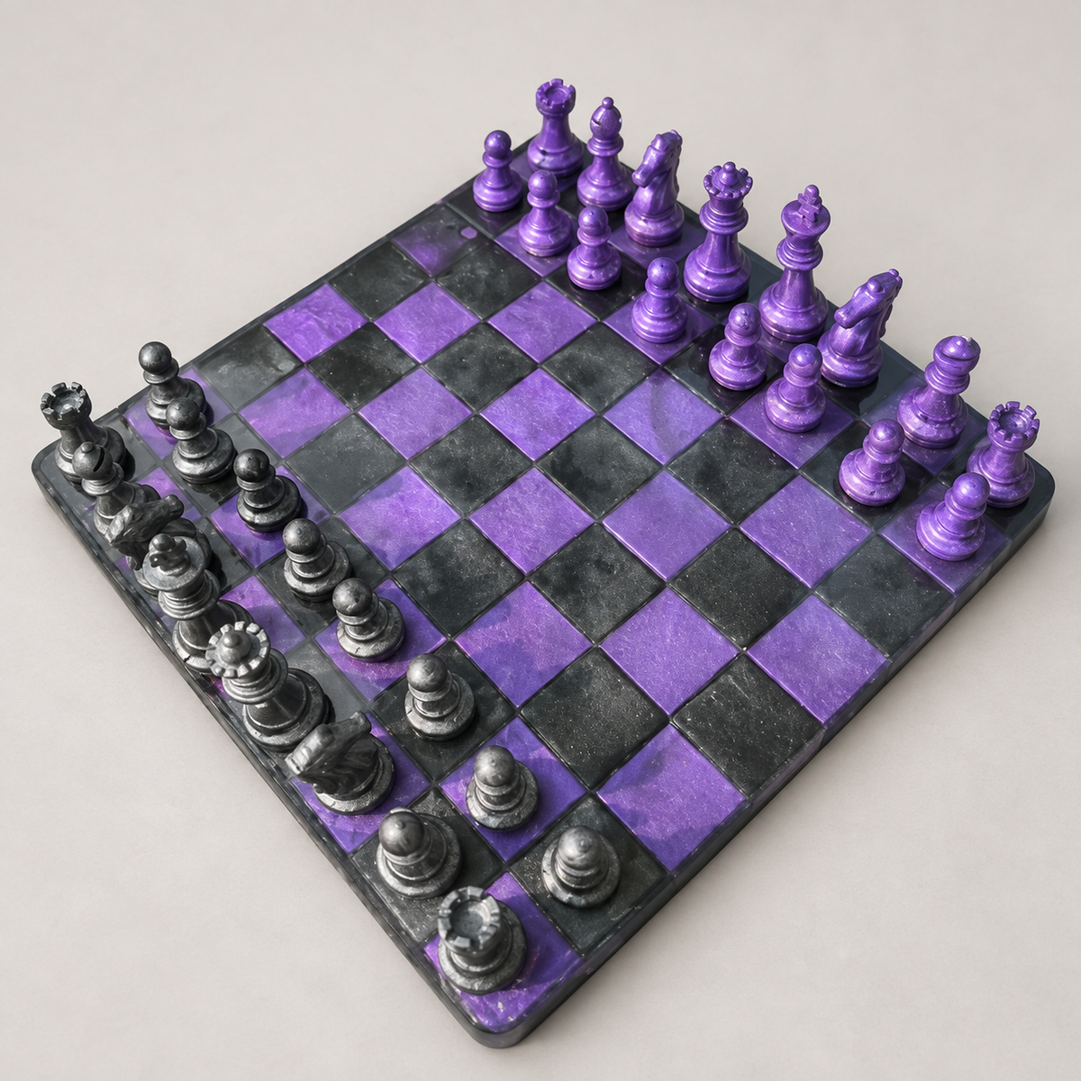 Purple and charcoal resin chessboard and matching pieces on a neutral background