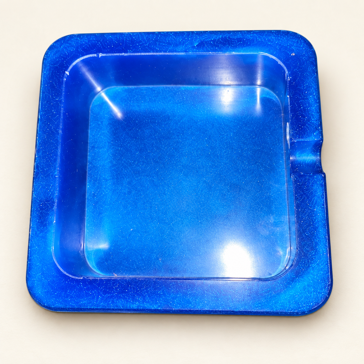 blue shimmer small square resin ashtray with one notch on cream background